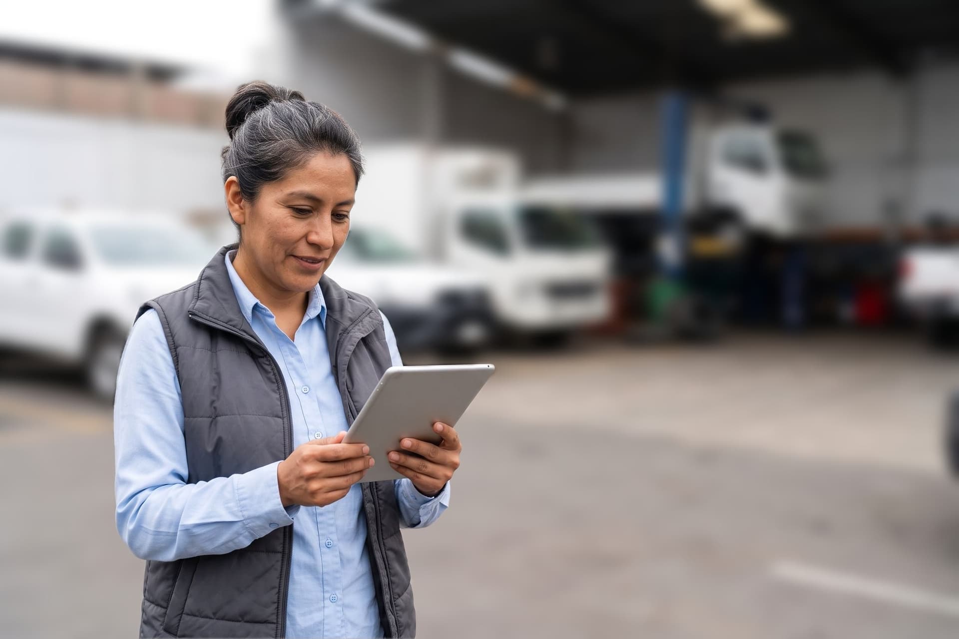 Jefa de flota revisando una tablet en un taller de vehículos