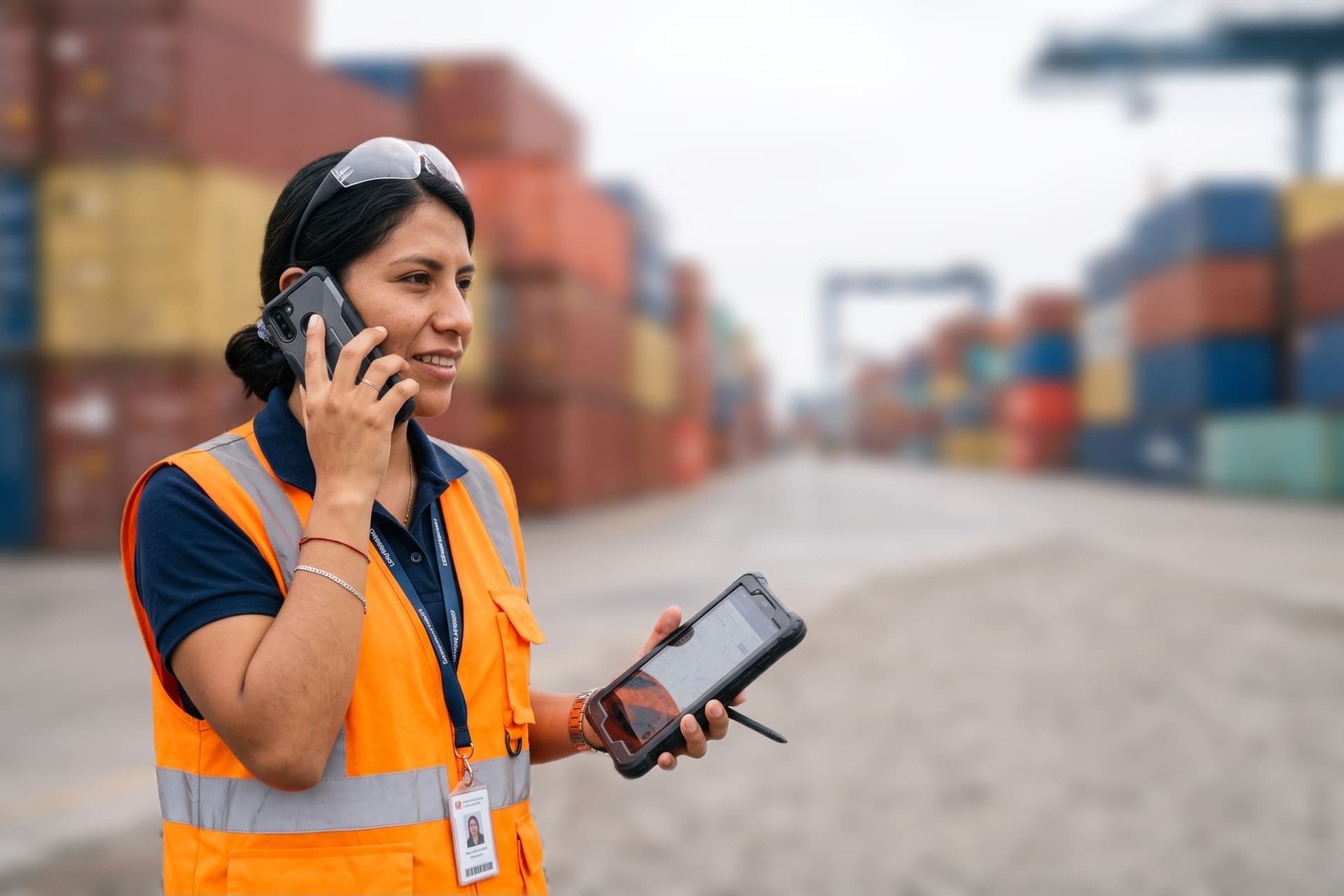 Coordinadora de operaciones hablando por teléfono en un patio de contenedores